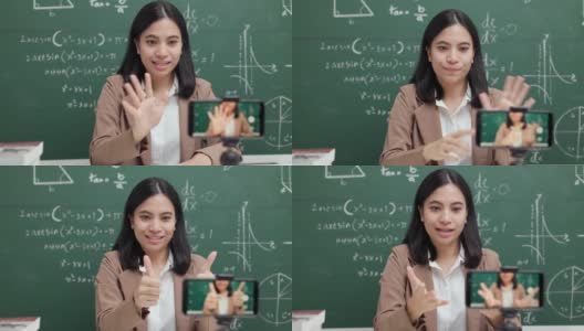 年轻的亚洲女教师坐在和学生视频会议。女教师在课堂上通过智能手机在线课程直播培训数学。高清在线视频素材下载
