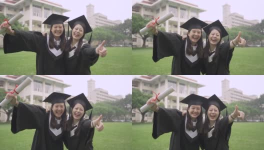 自拍回忆真实的时刻。两个开朗的亚洲毕业生自拍。迷人的女大学生最好的朋友穿着长袍和臼板在夏天的草地上。高清在线视频素材下载