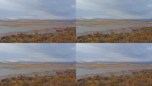 中国甘肃甘南尕海国家级自然保护区公园，宁静的湖水和五彩缤纷的植物在秋天，雪山和多云的天空背景美丽的风景。高清在线视频素材下载