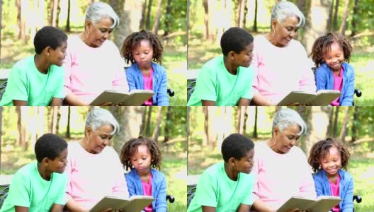 祖母和孙辈一起在户外看书或平板电脑。高清在线视频素材下载