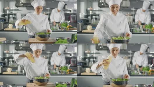 在一家著名的餐厅，女厨师准备沙拉，广告油。她在一家现代化的大厨房工作。高清在线视频素材下载
