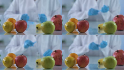 研究台上的新鲜水果，实验室工作人员开发维生素精华，转基因食品高清在线视频素材下载