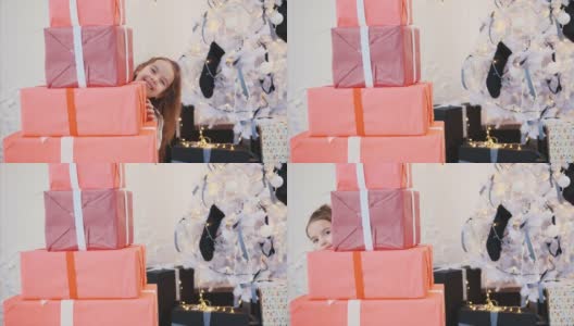 可爱的小女孩为她的朋友和家人准备了圣诞礼物，她从一堆红色礼品盒后面偷看出来。高清在线视频素材下载