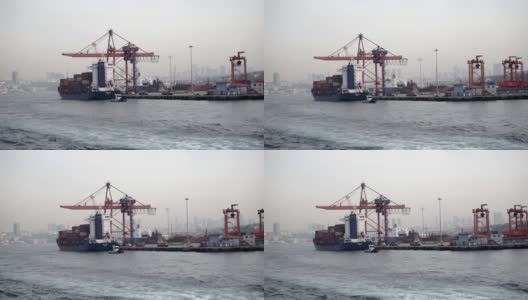 一艘装满铁集装箱的大型货船用起重机停靠在港口高清在线视频素材下载