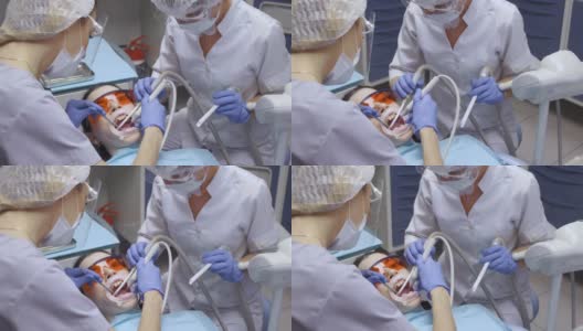 两个年轻的女牙医与眼镜工作的病人刷牙和检查病人，白色外套和面具的特写高清在线视频素材下载