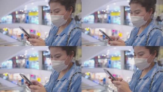 迷人的亚洲女性休闲服戴口罩防毒手用智能手机数码设备在商场超市背景高清在线视频素材下载