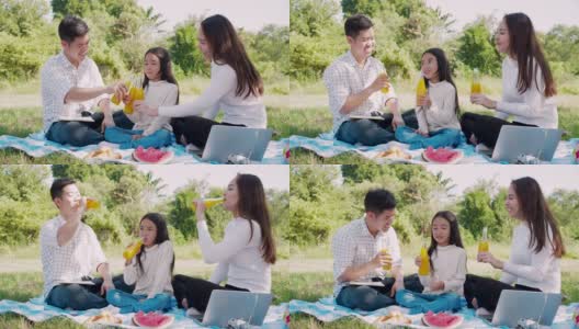 幸福的家庭野餐。亚洲父母(父亲，母亲)和小女孩喝橙汁，并有乐趣和享受自己一起在野餐布在绿色花园高清在线视频素材下载