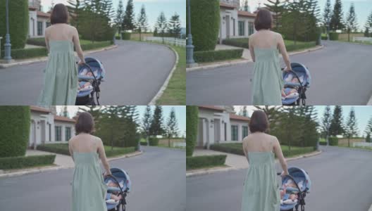 亚洲妇女母亲走在户外的婴儿在婴儿推车周围的街道村庄晚上。从家到花园，推着婴儿车散步放松。微笑快乐的家庭。高清在线视频素材下载