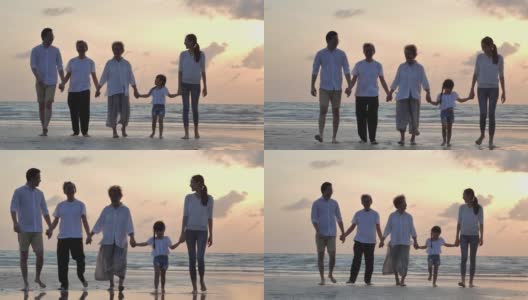 剪影中，快乐的亚洲大家庭五人手牵着手，走向日落海边的沙滩冲浪。幸福在自然的概念。高清在线视频素材下载
