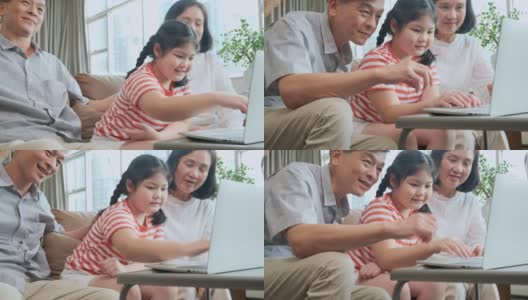 姥姥姥爷教小孙女用笔记本电脑坐在沙发上，幸福的关系纽带一代亚洲家庭花时间在家里一起玩笔记本电脑高清在线视频素材下载