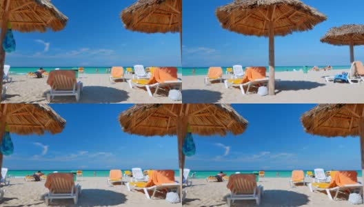 游客在热带海滩上的茅草伞下休息。高清在线视频素材下载