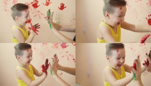 年轻的母亲和她的小男孩在他们的手混合颜色，你留下美丽的手印在墙上。母亲和孩子的概念。Slowmotion。高清在线视频素材下载
