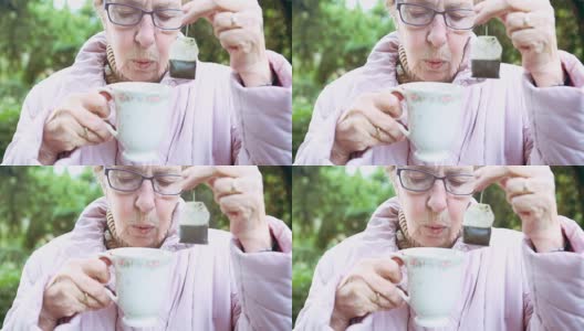 年长的女人拿着一个茶包和杯子的Cinemagraph高清在线视频素材下载