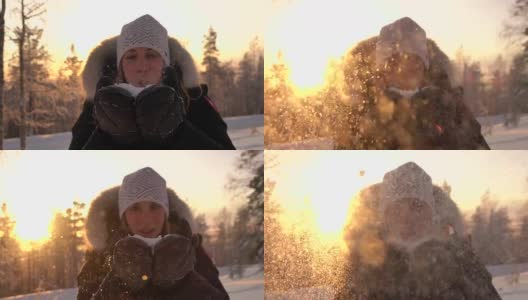 慢镜头:在神奇的冬天，年轻女子在夕阳下吹着雪花高清在线视频素材下载