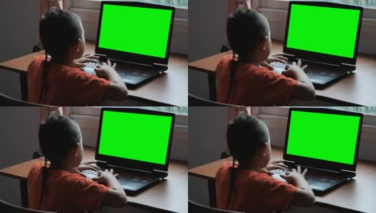 亚洲男孩7岁用笔记本电脑在家里搜索互联网信息的绿色屏幕。日常生活中的技术概念。高清在线视频素材下载
