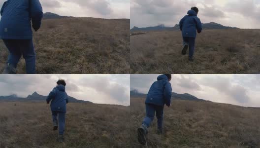 一个小男孩在山坡上跑到雾气弥漫的山上。慢动作视频高清在线视频素材下载
