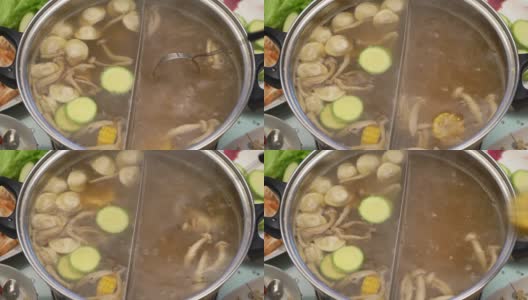 概念火锅亚洲美食。在桌上沸腾的肉汤。玉米放进肉汤里煮高清在线视频素材下载