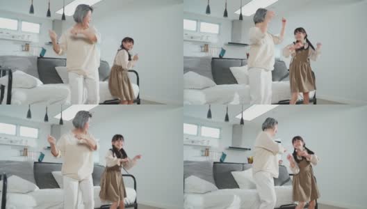 亚裔家庭小女孩和爷爷奶奶在客厅一起跳舞。孩子和老人带着笑脸运动，心情愉快。可爱的家庭和活动理念的快乐时刻高清在线视频素材下载