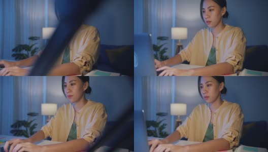 亚洲职业女性，穿着休闲服装，晚上在家里客厅用笔记本电脑工作。高清在线视频素材下载