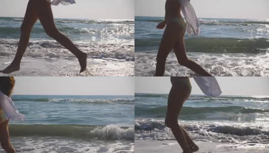 女性的脚在潮湿的沙子和海浪在海滩的海水上奔跑的特写。年轻女子在岸边奔跑的双腿。光着脚的女孩在海边。暑假或假日概念。慢动作侧视图低角度视图高清在线视频素材下载