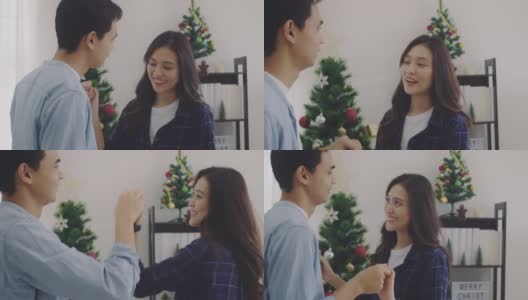 在圣诞树的背景下，年轻的亚洲情侣情侣在圣诞节和快乐的新年节日一起跳舞。圣诞节庆祝情人的概念。4 k慢动作。高清在线视频素材下载