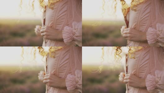 一头卷发的女孩穿着粉红色的裙子，在紫色的田野中解开束胸衣上的纽扣高清在线视频素材下载