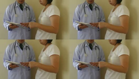 身穿白制服大褂的专业医生在平板电脑上展示结果，并咨询女性患者。医院、诊所的专业保健理念高清在线视频素材下载
