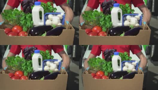 特写拍摄一名快递员在工作时间内手拿一盒有机食品摆姿势高清在线视频素材下载