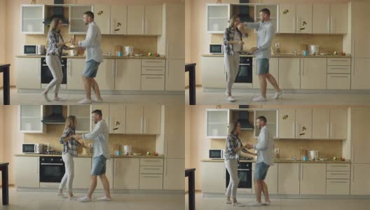 迷人的年轻快乐的夫妇有乐趣跳舞，同时在厨房做饭在家里高清在线视频素材下载