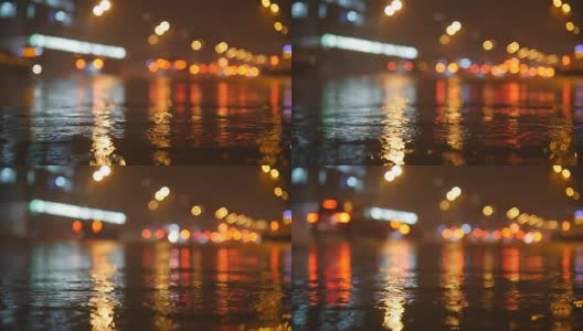 五颜六色的交通灯在水中倒映，夜晚的城市街道上有小雨滴。慢动作视频高清在线视频素材下载
