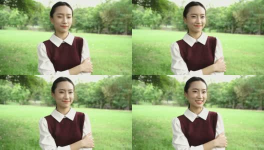 年轻迷人的亚洲女人微笑与双臂交叉在校服在公园户外高清在线视频素材下载