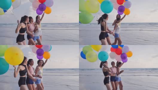 一群女朋友在海滩上玩着气球，背景是蓝天。在夏日阳光明媚的阳光下，朋友们在沙滩上嬉戏。假期——iStock高清在线视频素材下载