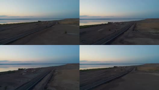 日落时分，汽车在沙漠中间的空旷道路上行驶的鸟瞰图高清在线视频素材下载