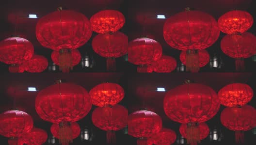 一个红色圆灯笼的特写，里面有一个灯泡，在中国新年庆祝期间的晚上在风中摇摆高清在线视频素材下载