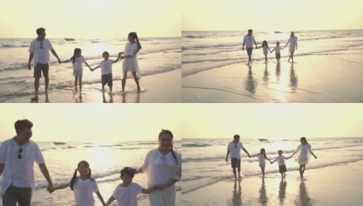 慢镜头剪影的年轻亚洲家庭父母与两个孩子的男孩和女孩走在海滩上与微笑一起在夏季日落。快乐的家庭在假期放松和乐趣。高清在线视频素材下载