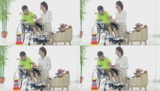 妇女志愿者和脑瘫残疾男孩在残疾人庇护所玩教育游戏高清在线视频素材下载