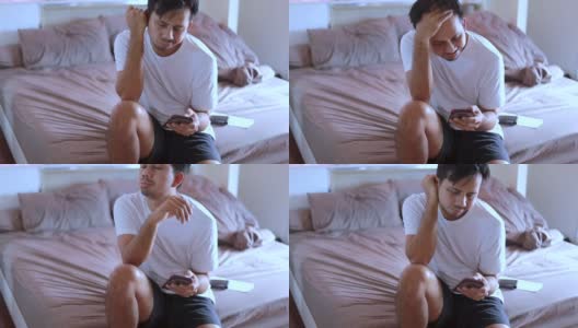一名亚洲男子在床上使用智能手机高清在线视频素材下载