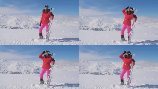 女人拿着滑雪板，戴着护目镜，站在雪山的背景高清在线视频素材下载
