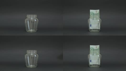 一名男子将欧元放入玻璃罐中储存。黑色背景上的槽式玻璃罐。高清在线视频素材下载
