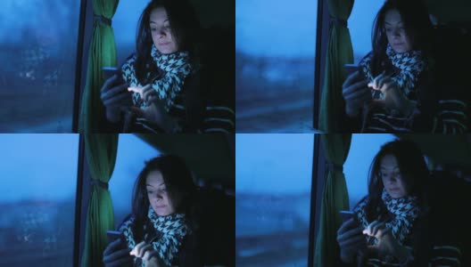 一名女子在晚上乘公交车时使用手机。女孩晚上上网查邮件高清在线视频素材下载