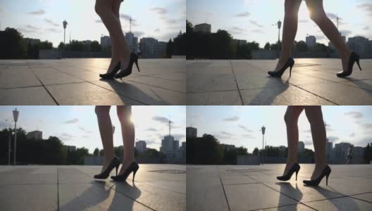 在日落时分，穿着黑色高跟鞋走在城市广场上的苗条女性腿。年轻女商人的脚穿着高跟鞋走在城市的街道上。低角度视角慢动作特写高清在线视频素材下载