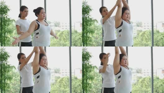 超重肥胖的亚洲妇女在垫子上与女教练练习瑜伽来减肥高清在线视频素材下载