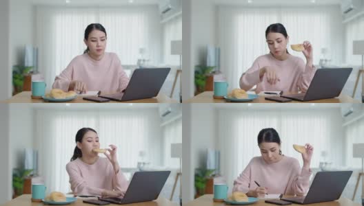 年轻迷人美丽的亚洲女性饿了吃甜甜圈，吃零食吃满嘴看电脑笔记本在家里在忙碌的工作，从家里多任务不健康的饮食生活理念。高清在线视频素材下载