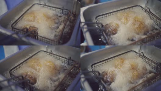 在厨房用滚烫的油筐煎炸香脆鸡翅高清在线视频素材下载