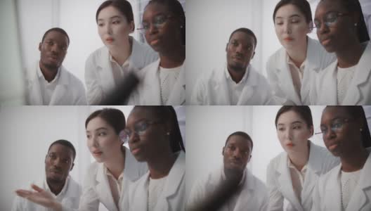 多元化的团队在现代化的实验室中工作。女人和男人在研究过程中讨论高清在线视频素材下载