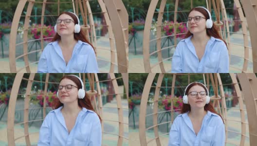 白人英俊的年轻女子戴着耳机，听着音乐在城市公园在日落高清在线视频素材下载