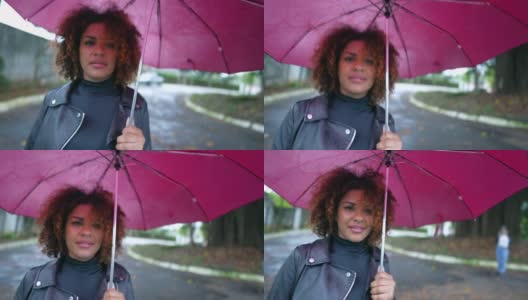 巴西妇女撑着伞在雨中走在城市外面高清在线视频素材下载