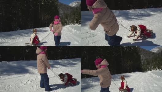 冬天，两个快乐美丽的孩子在山上白雪覆盖的森林里玩雪橇。哥哥和妹妹。那个女孩用雪橇载着那个男孩在白雪上。高清在线视频素材下载