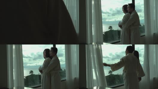 4k视频场景的亚洲夫妇在早上醒来时，睡袍和打开窗户上的窗帘在豪华酒店卧室，生活和休闲概念高清在线视频素材下载