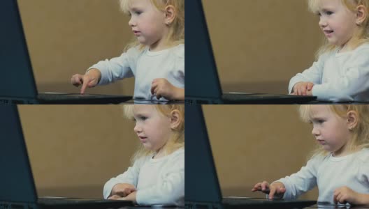 特写:一个三岁的小女孩独立地把卡通片放在笔记本电脑上，在家里的屏幕上看。高清在线视频素材下载